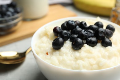 Photo of Delicious rice pudding with blueberries on table, closeup