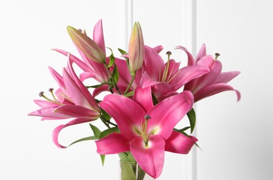 Photo of Beautiful pink lily flowers against white wall, closeup