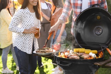 Photo of People with drinks having barbecue party outdoors, closeup