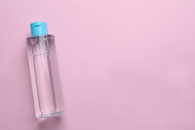 Photo of Micellar water on pink background, top view. Space for text