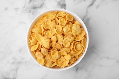 Photo of Tasty crispy corn flakes in bowl on white marble table, top view. Breakfast cereal