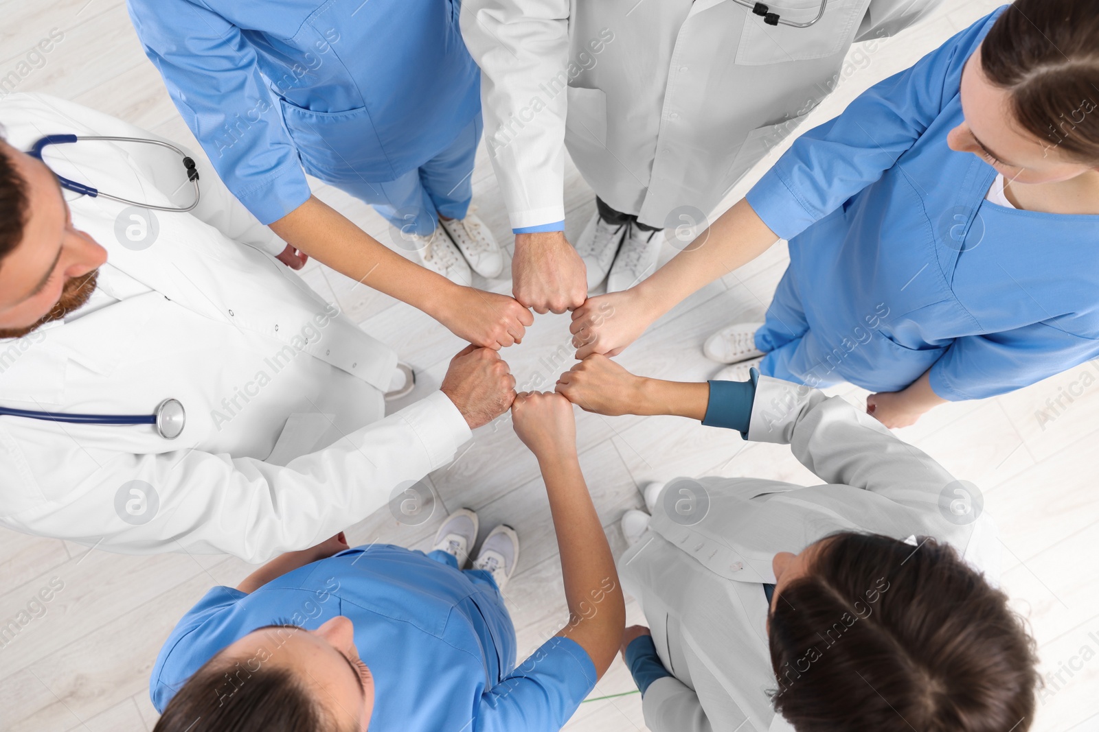 Photo of Team of medical doctors putting hands together indoors, above view