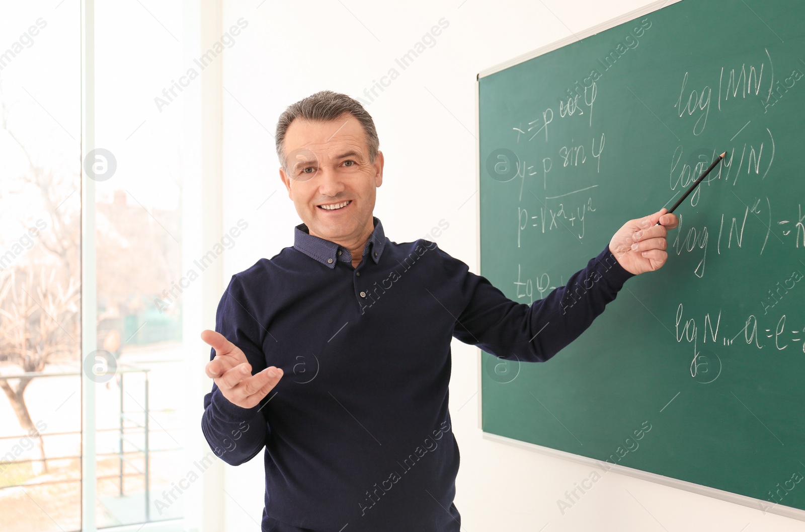 Photo of Portrait of male teacher near blackboard in classroom