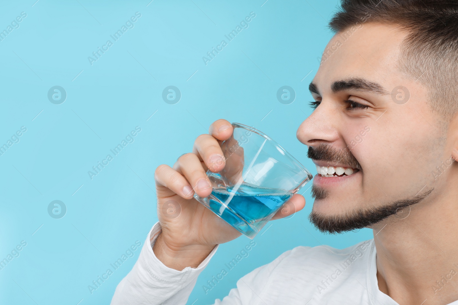 Photo of Man with glass of mouthwash on color background, space for text. Teeth and oral care