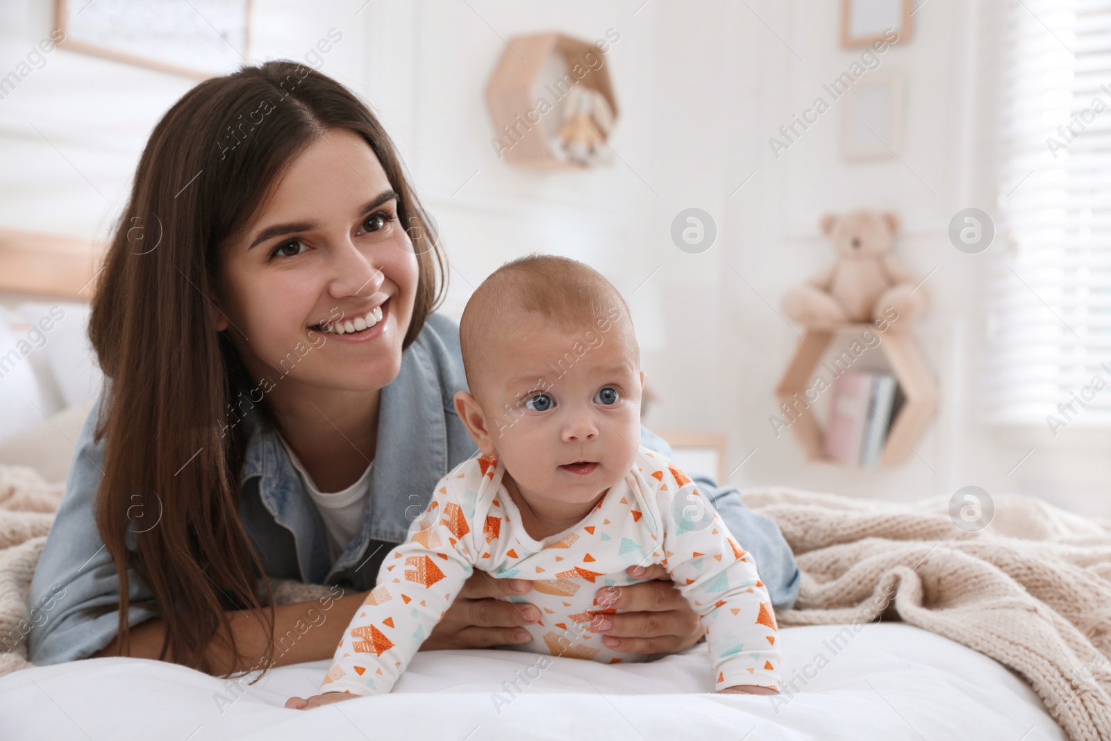 Photo of Mother with her cute baby on bed at home