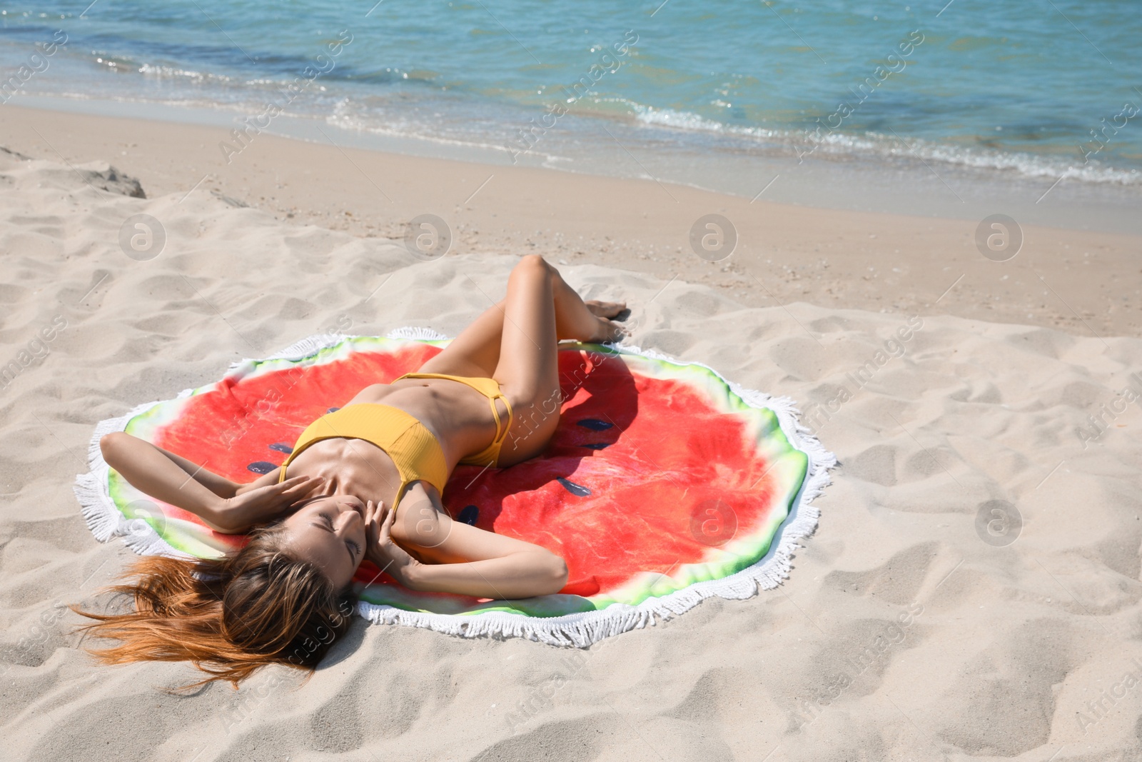 Photo of Beautiful woman with beach towel on sand near sea