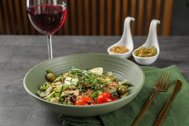 Tasty dish with tarragon, salad dressings and glass of wine served on grey table