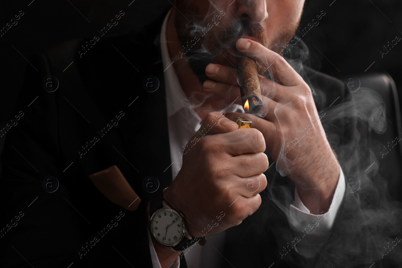 Photo of Man lightning cigar on black background, closeup