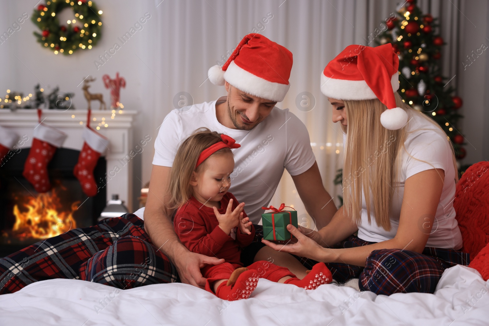 Photo of Happy family with Santa hats in room decorated for Christmas