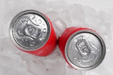 Photo of Energy drinks in wet cans on ice cubes, flat lay