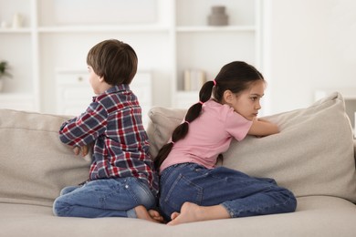 Upset brother and sister on sofa at home