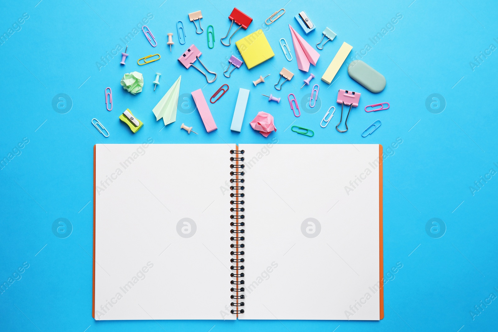 Photo of Back to school. School stationery and paper planes near notebook on light blue background, flat lay