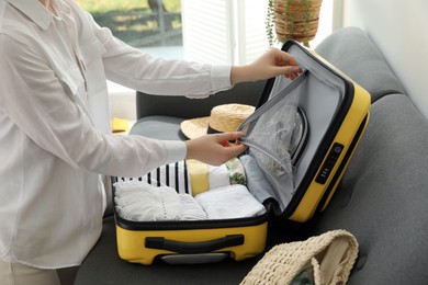 Woman packing suitcase for trip in living room, closeup