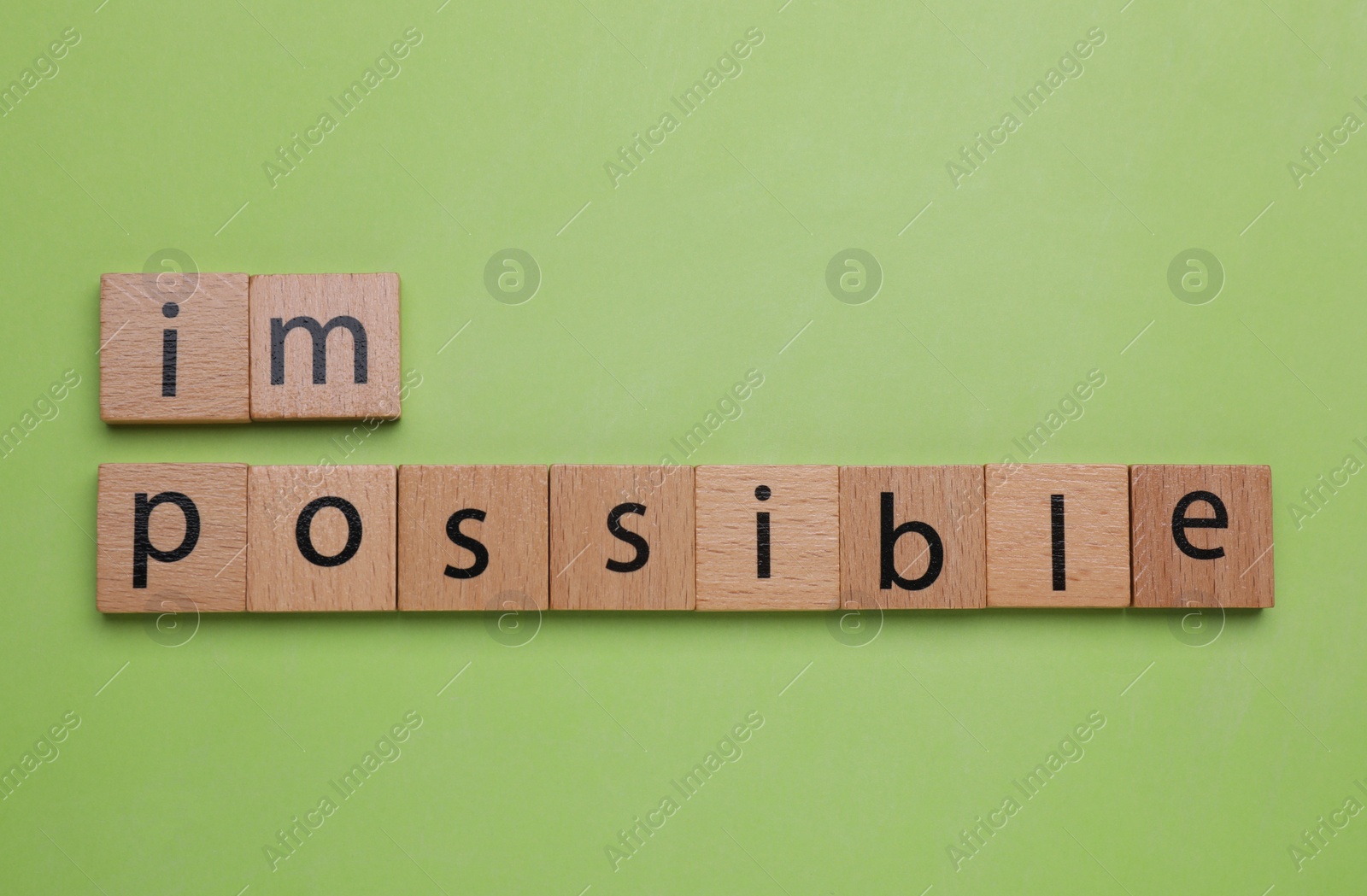 Photo of Motivation concept. Changing word from Impossible into Possible by removing wooden squares on light green background, flat lay