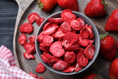 Photo of Freeze dried and fresh strawberries on black wooden table, top view