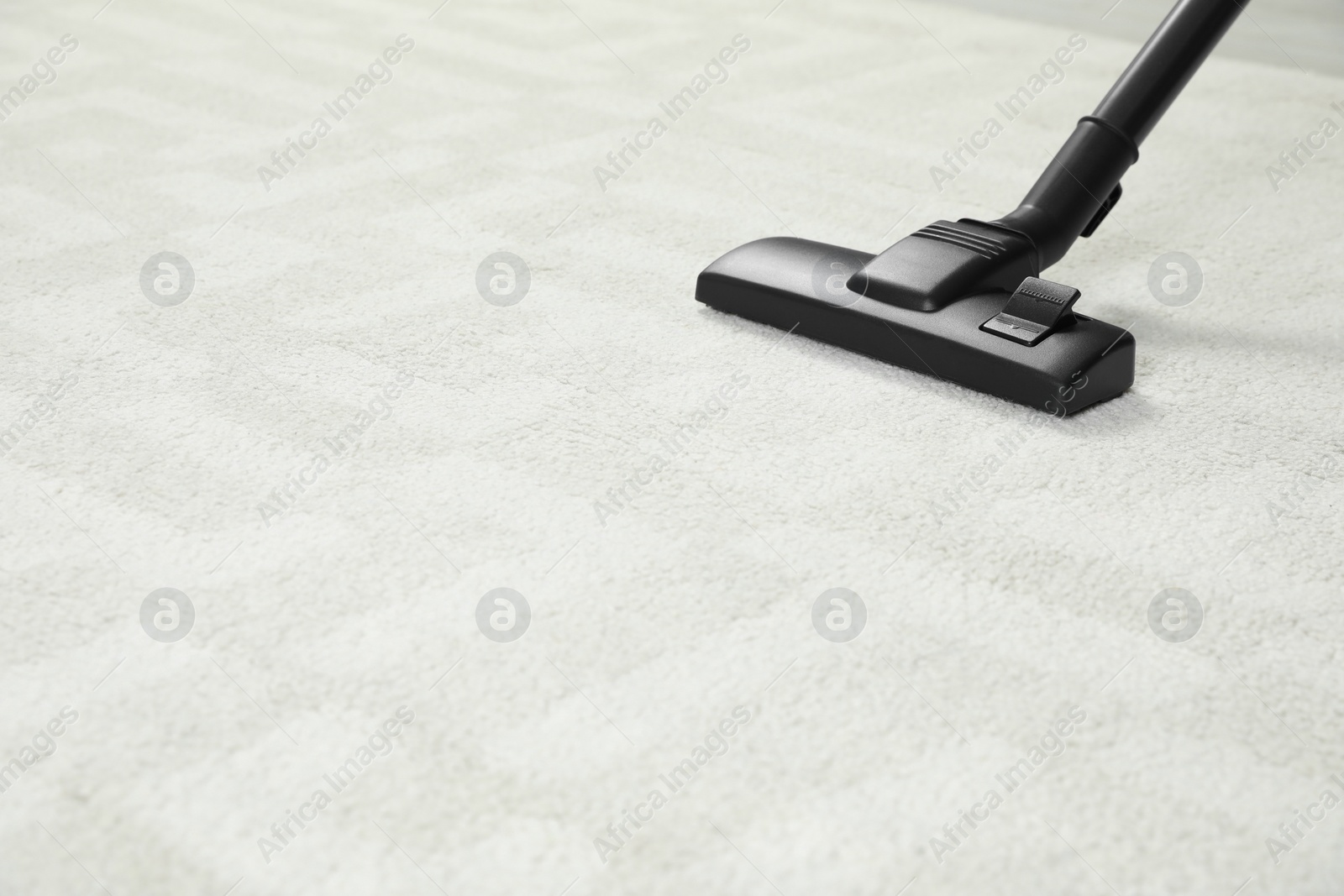 Photo of Removing dirt from white carpet with modern vacuum cleaner. Space for text