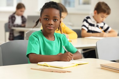 Portrait of cute little boy studying in classroom at school