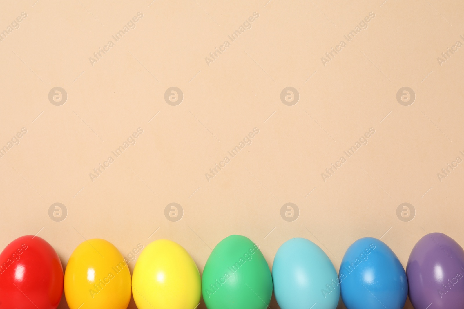 Photo of Easter eggs on beige background, flat lay. Space for text