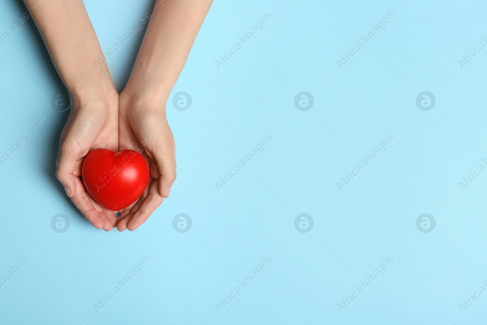 Photo of Woman holding heart on blue background, top view with space for text. Donation concept