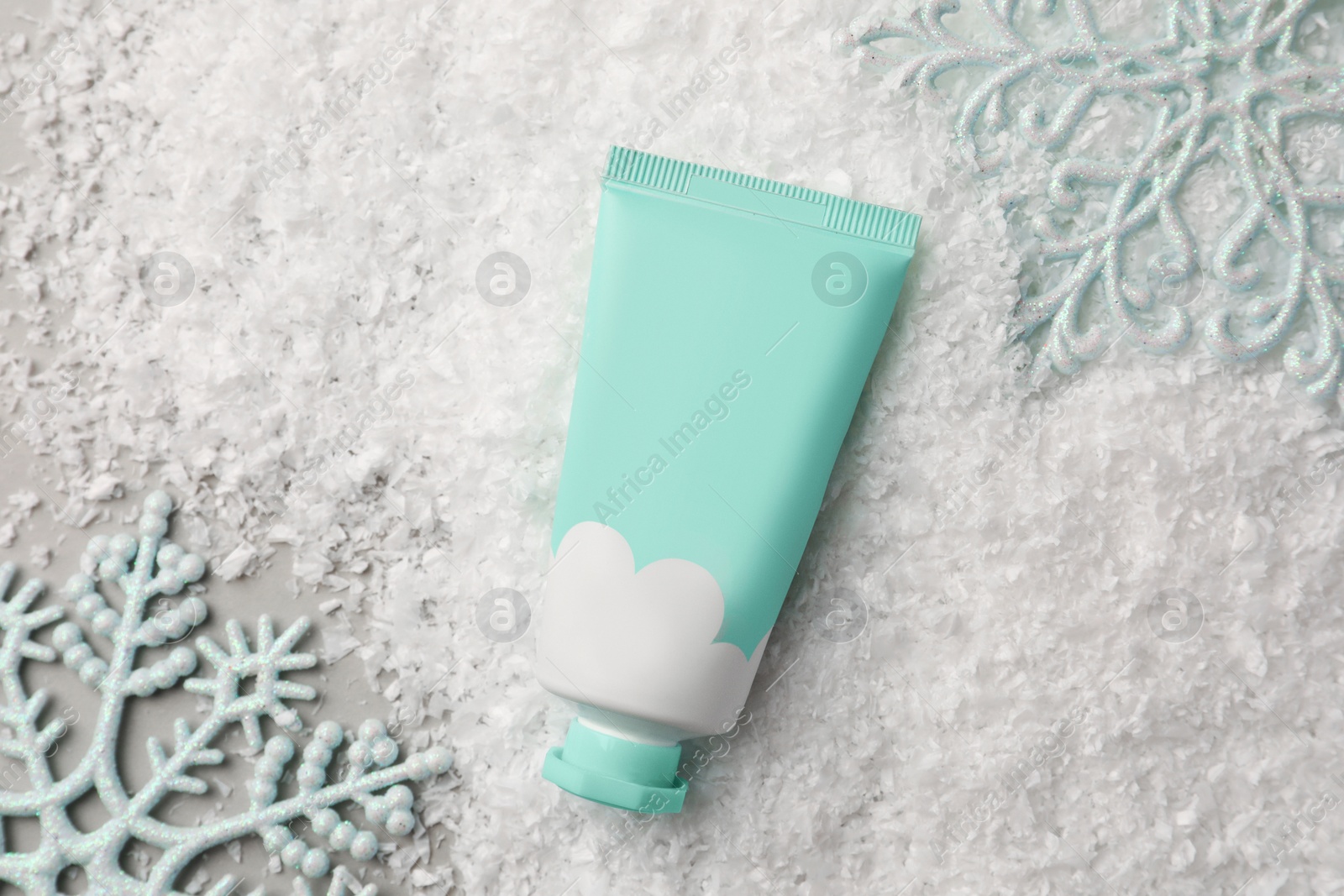 Photo of Winter skin care. Hand cream and decorative snowflakes on light grey background, flat lay