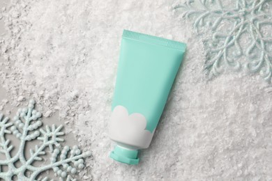 Winter skin care. Hand cream and decorative snowflakes on light grey background, flat lay