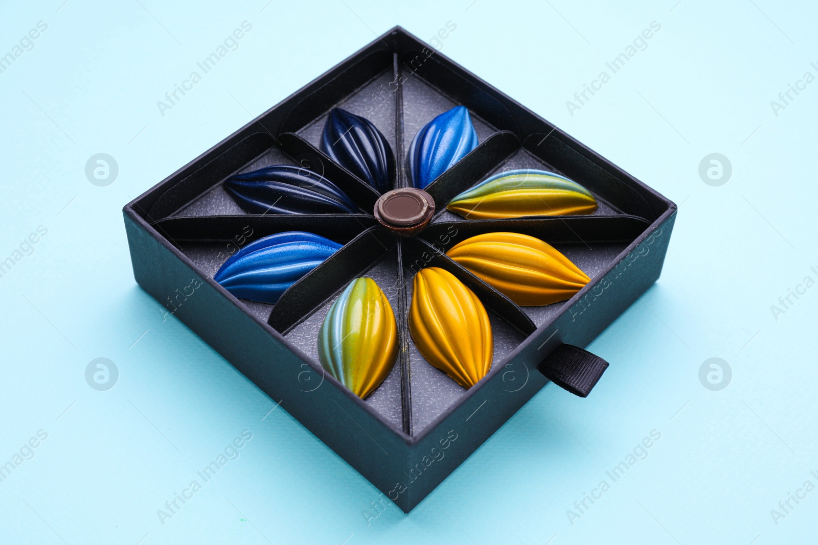 Photo of Box of tasty chocolate candies on light blue background