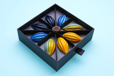 Box of tasty chocolate candies on light blue background