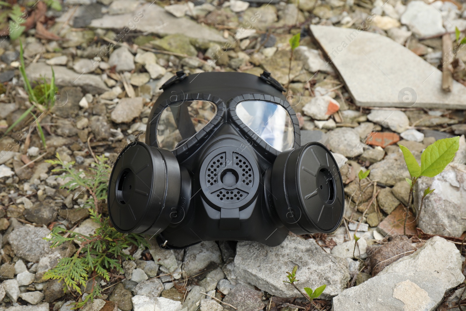 Photo of One gas mask on ground with stones outdoors