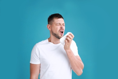 Photo of Man suffering from allergy on blue background