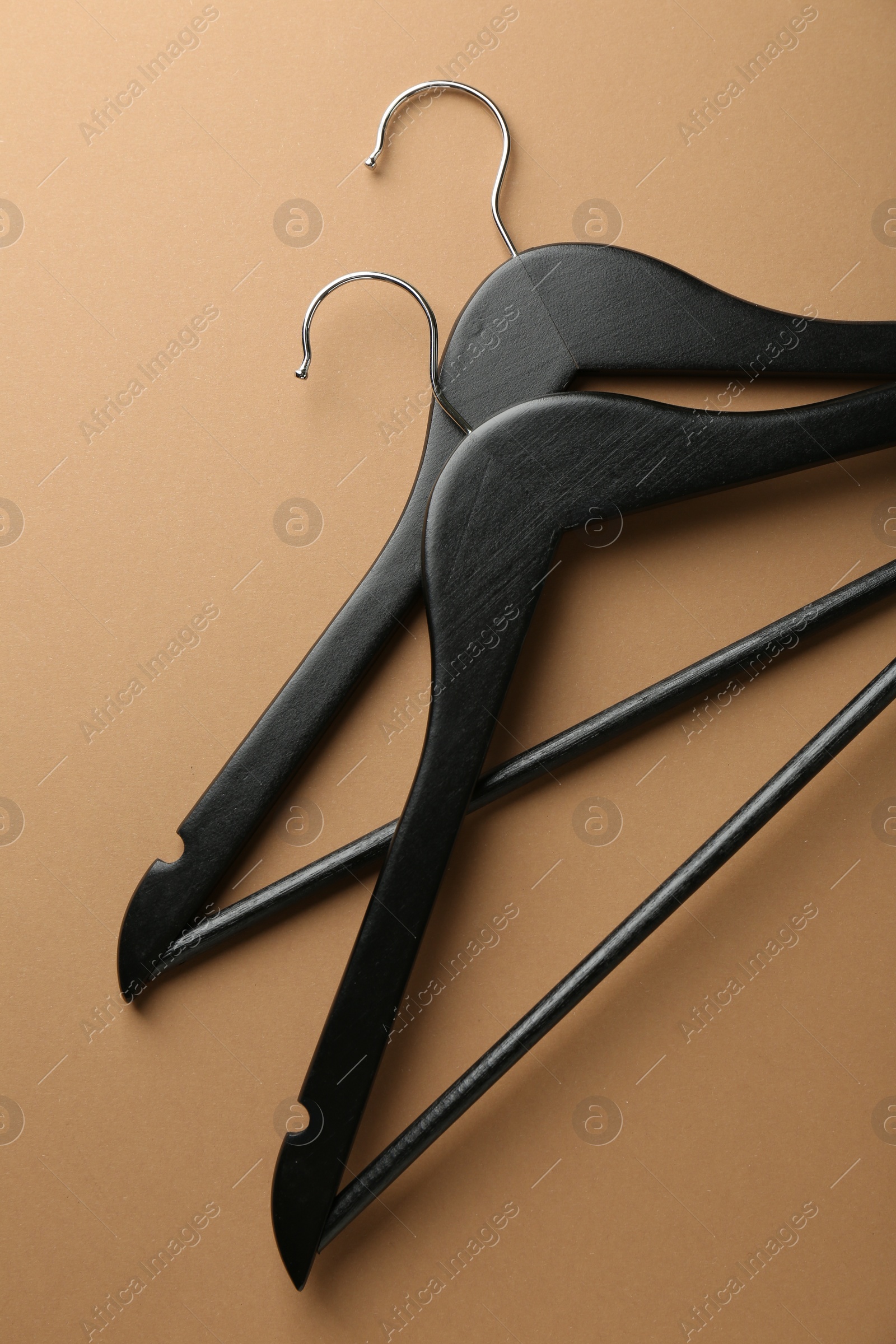 Photo of Black hangers on brown background, top view