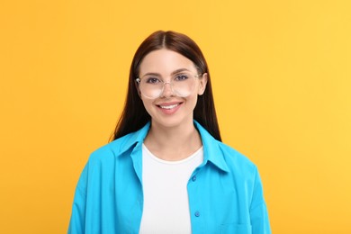 Photo of Portrait of smiling woman in stylish eyeglasses on orange background