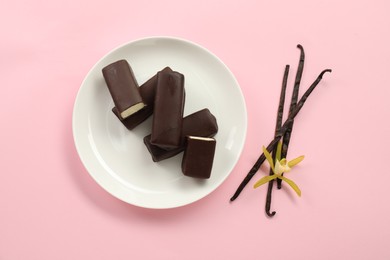 Photo of Glazed curd cheese bars, vanilla pods and flower on pink background, top view