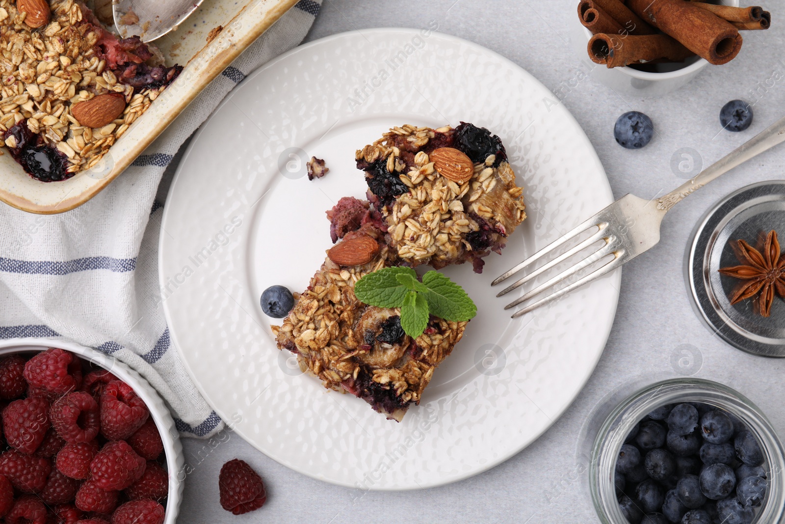 Photo of Tasty baked oatmeal with berries and almonds on light grey table, flat lay