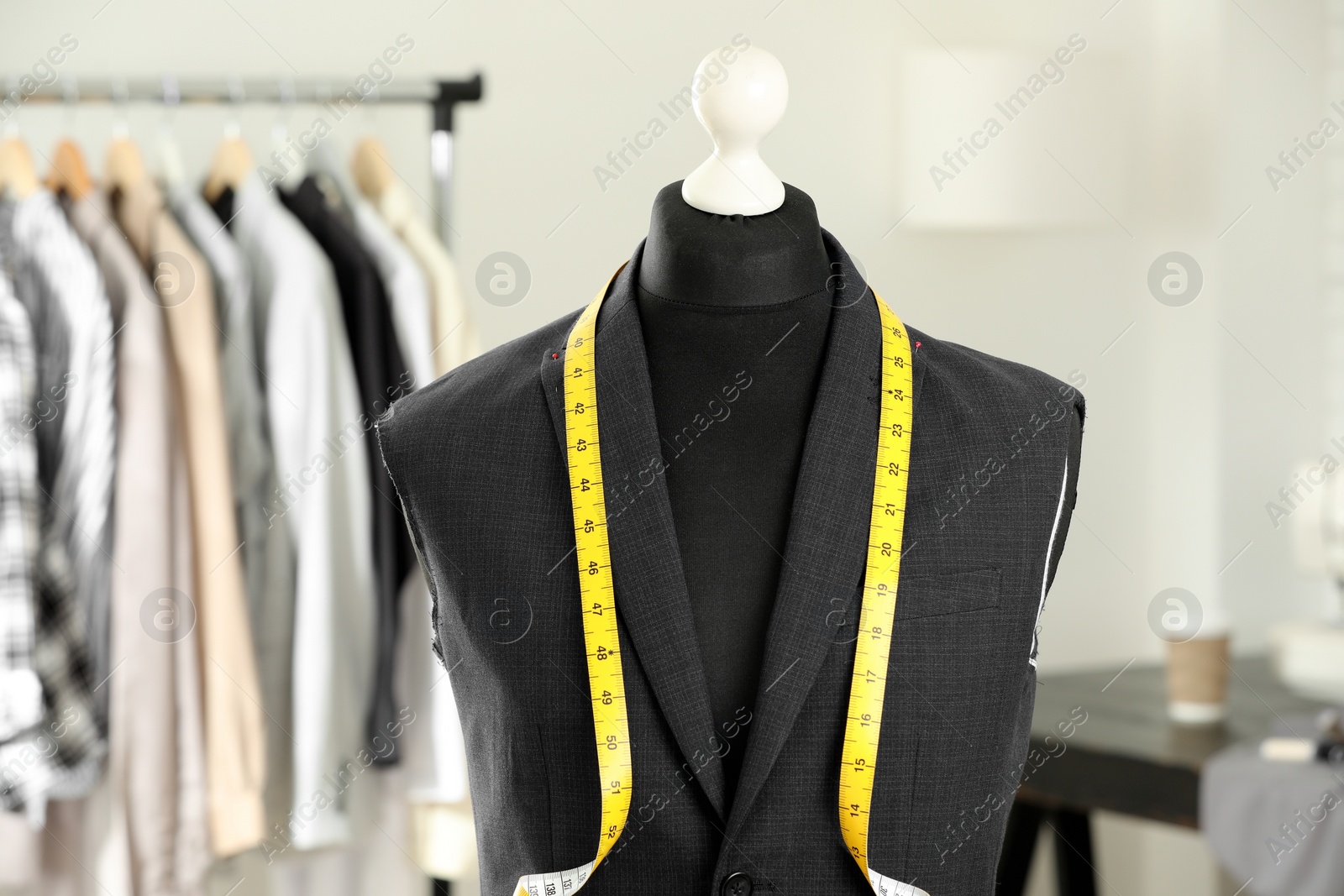 Photo of Mannequin with unfinished jacket and measuring tape in tailor shop