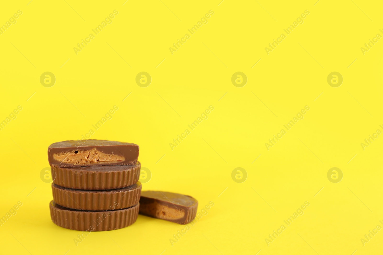 Photo of Sweet peanut butter cups on yellow background. Space for text