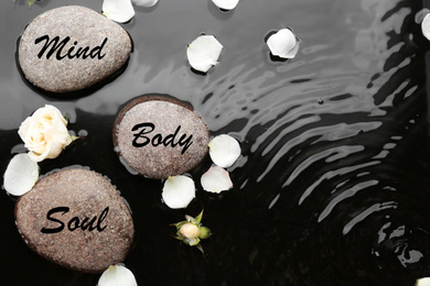 Photo of Spa stones with words Mind, Body, Soul and rose petals in water, flat lay. Zen lifestyle