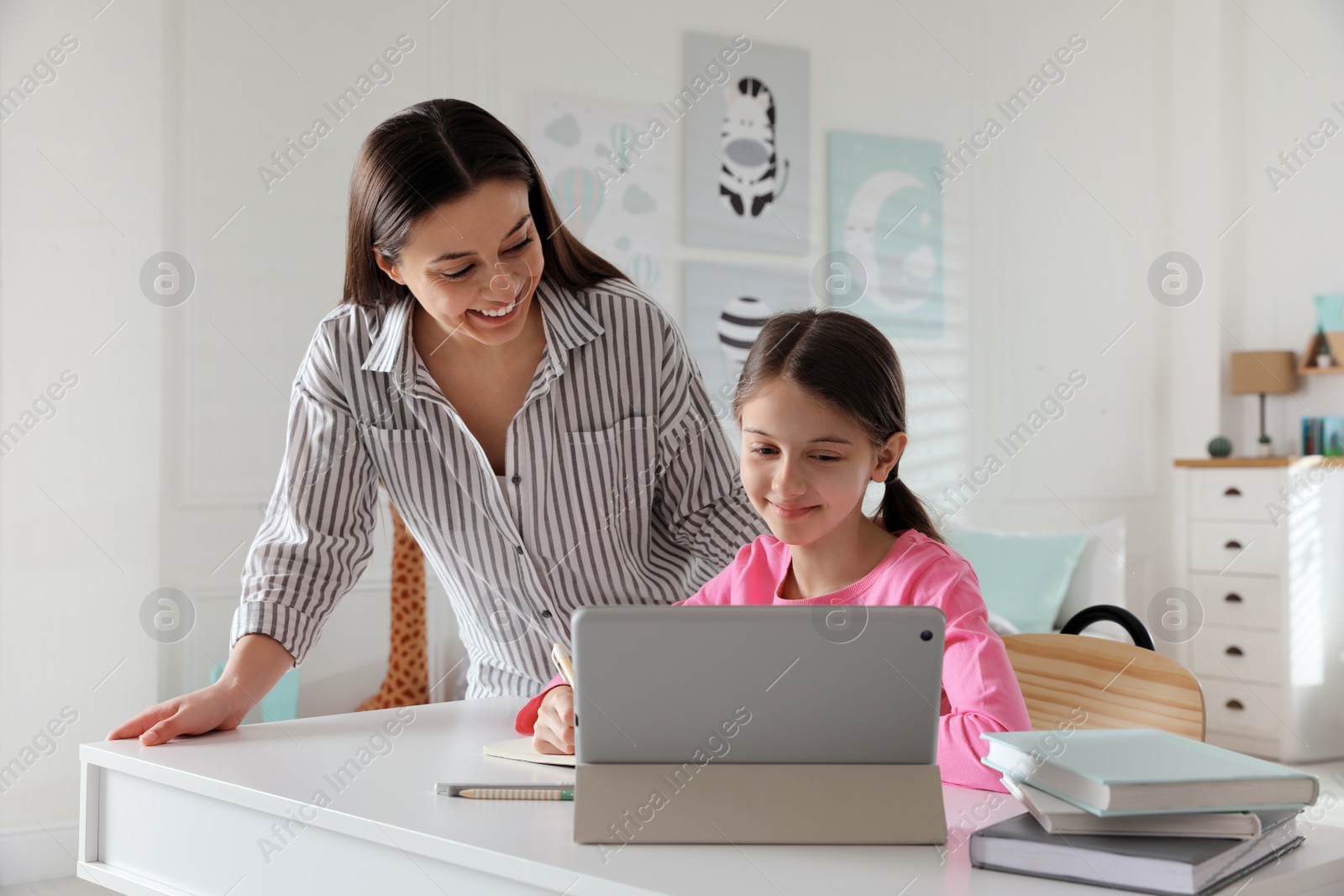 Photo of Mother helping her daughter doing homework with tablet at home