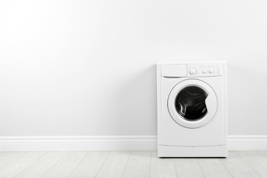 Photo of Modern washing machine near white wall, space for text. Laundry day