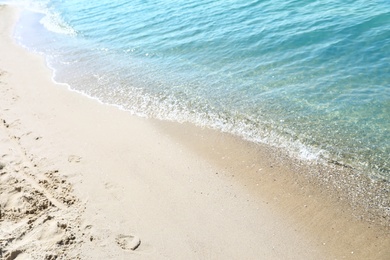 View of sea water and beach sand on sunny day