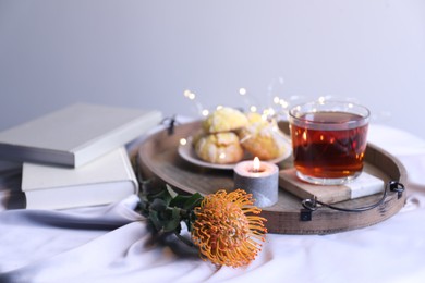 Photo of Composition with beautiful leucospermum flower, tasty tea and books. Cozy home atmosphere