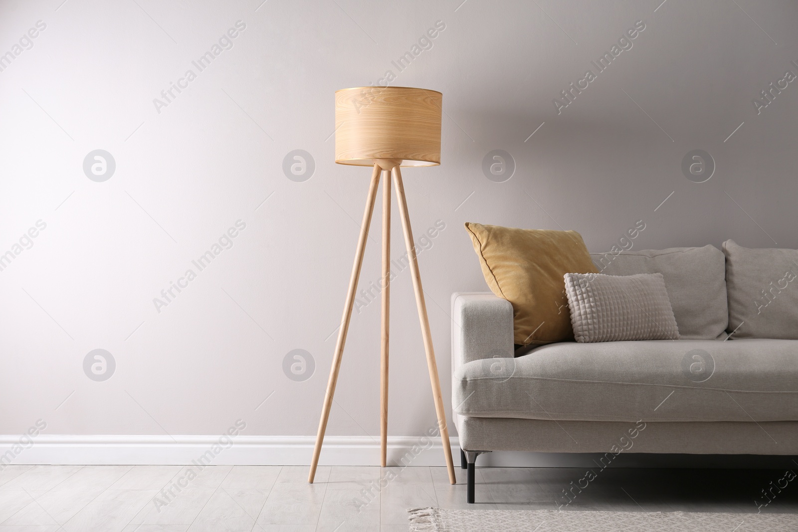 Photo of Stylish living room interior with comfortable sofa and tripod floor lamp. Space for text