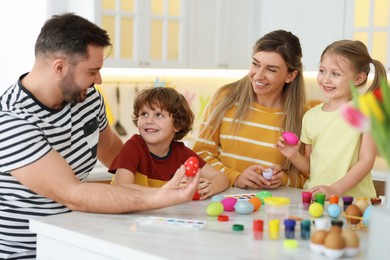 Happy Easter. Cute family with painted eggs at white marble table in kitchen