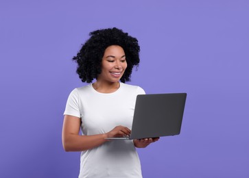 Photo of Happy young woman with laptop on purple background