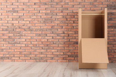 Photo of Empty wardrobe box against brick wall indoors. Space for text