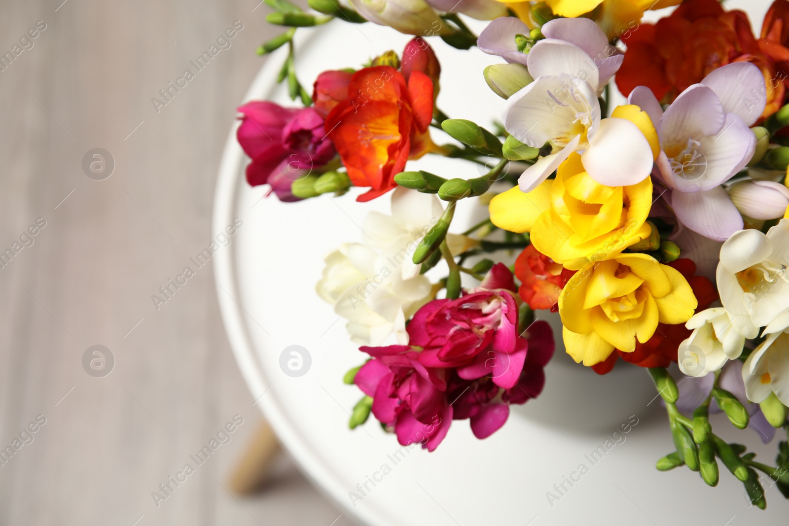 Photo of Bouquet of beautiful spring freesia flowers in vase on table. Space for text