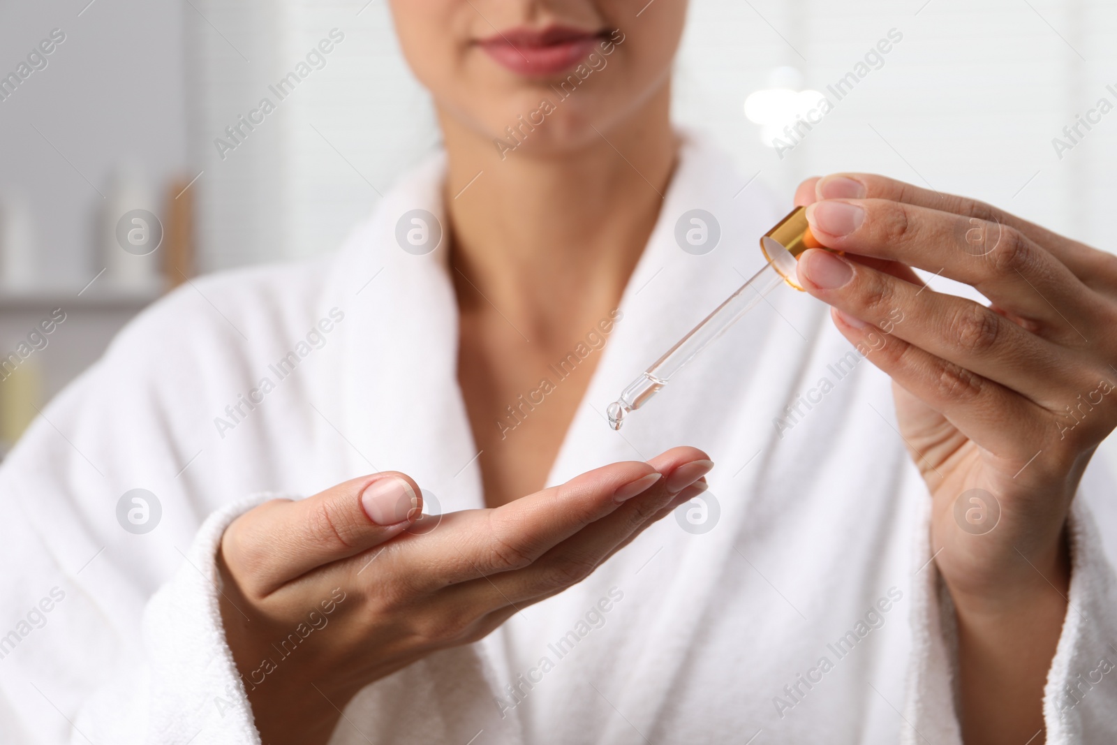 Photo of Woman applying cosmetic serum onto her hand on blurred background, closeup