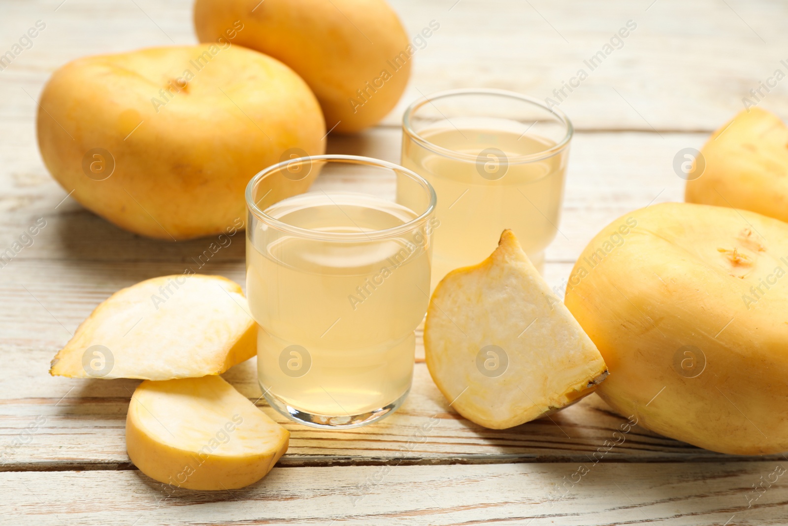 Photo of Glasses of freshly made turnip juice on white wooden table