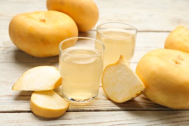 Photo of Glasses of freshly made turnip juice on white wooden table