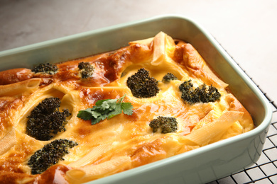 Photo of Tasty broccoli casserole in baking dish on cooling rack, closeup