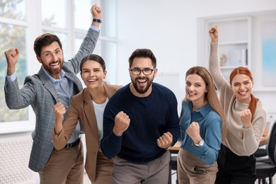 Photo of Team of employees celebrating success in office